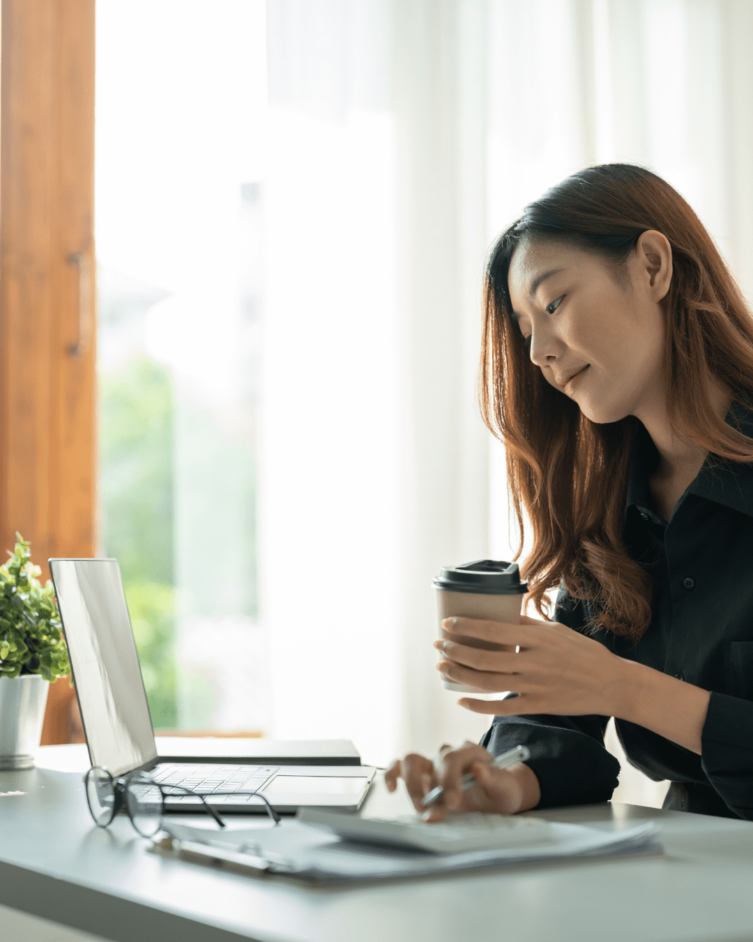 Woman working at her desk sipping coffee, symbolizing focused advertising strategies for company growth.