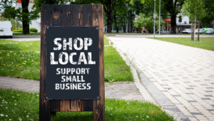 A sandwich board outside a small business displaying "Shop Local, Support Small Business," highlighting the power of local SEO for small businesses.