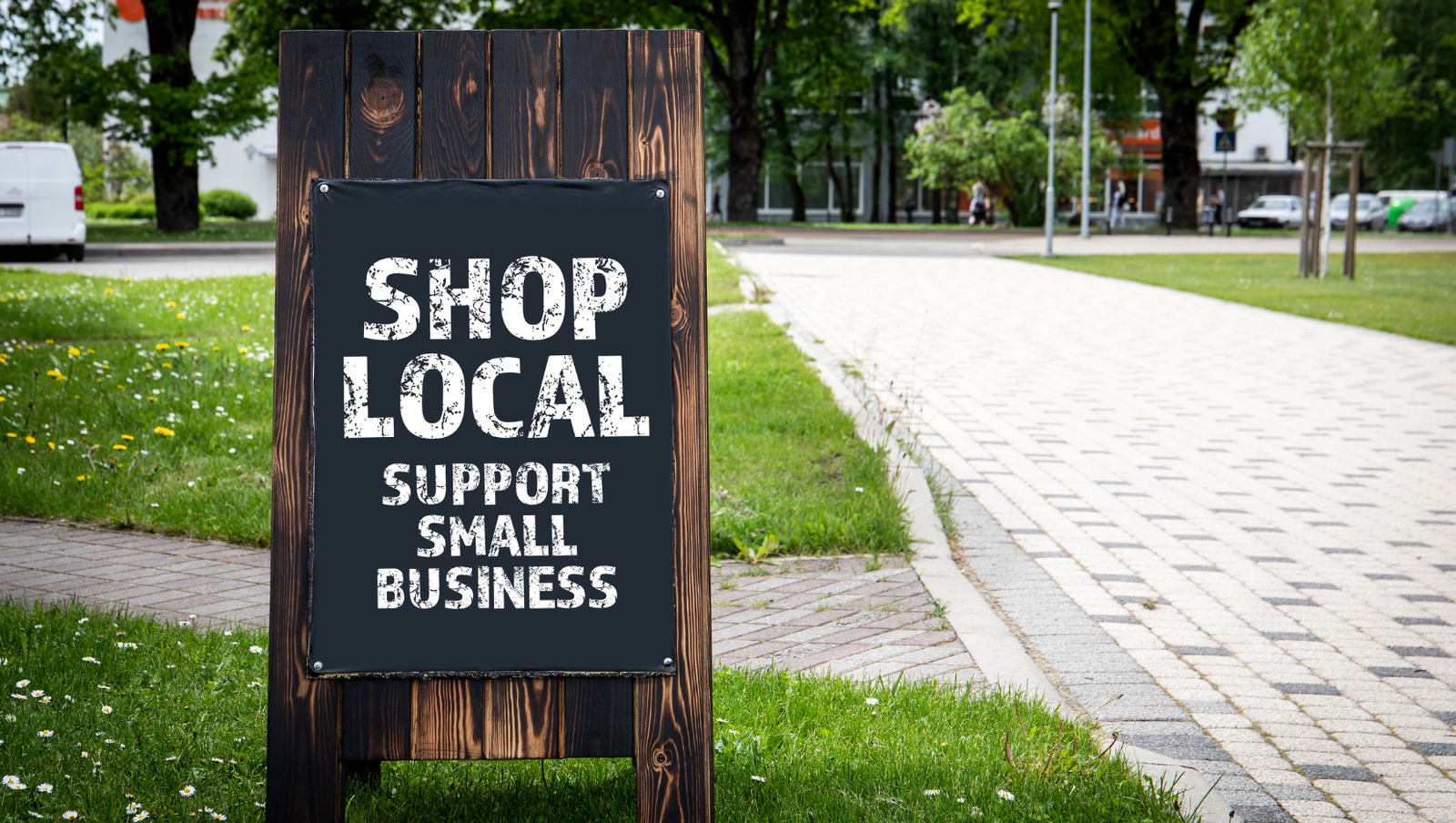 A sandwich board outside a small business displaying "Shop Local, Support Small Business," highlighting the power of local SEO for small businesses.
